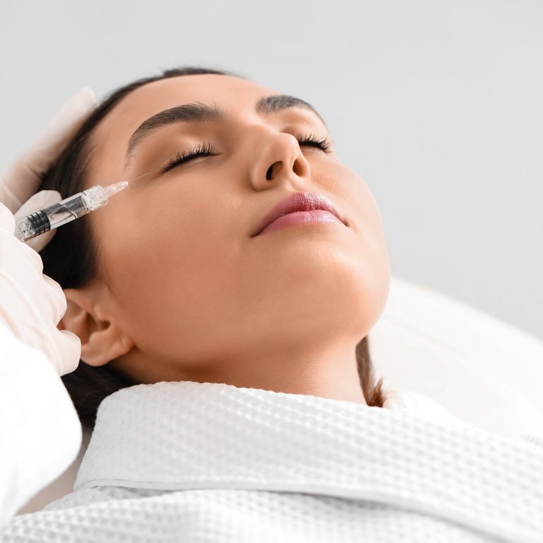 Young woman receiving filler injection in beauty  salon