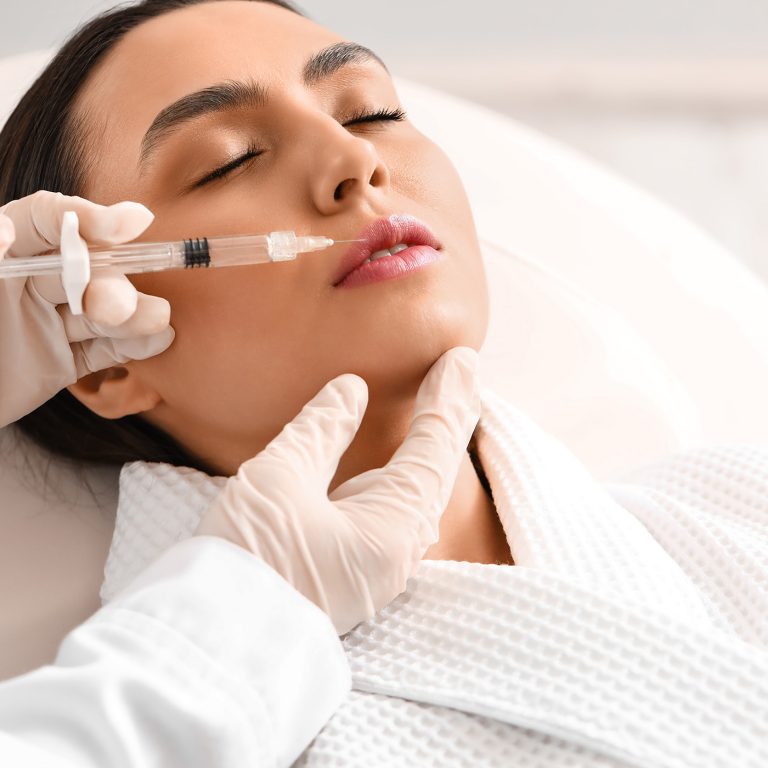 Young woman receiving filler injection in lips in beauty salon